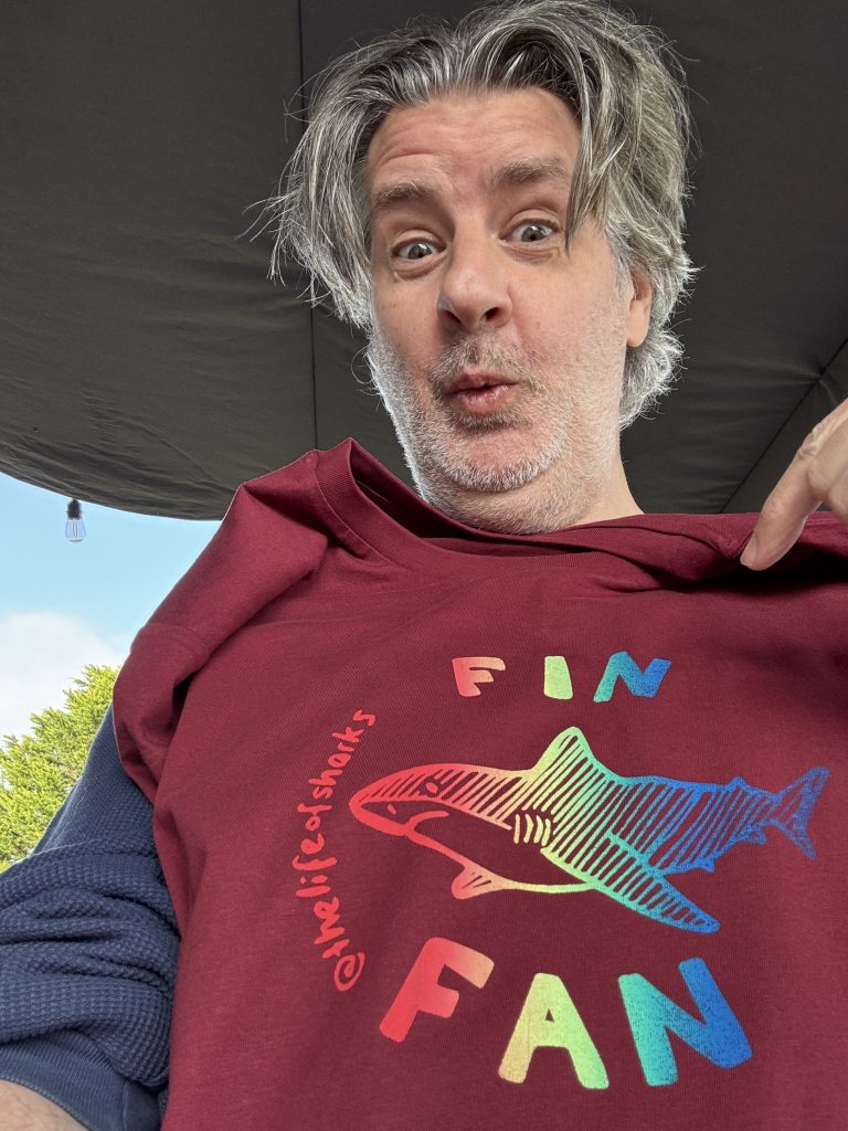 Christian holding up a finished rainbow Fin Fan T-shirt